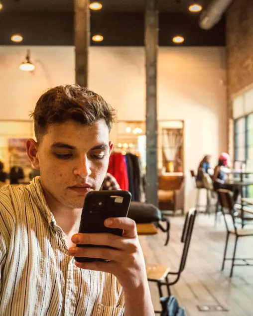 A man checking a business story on his phone in a cafe